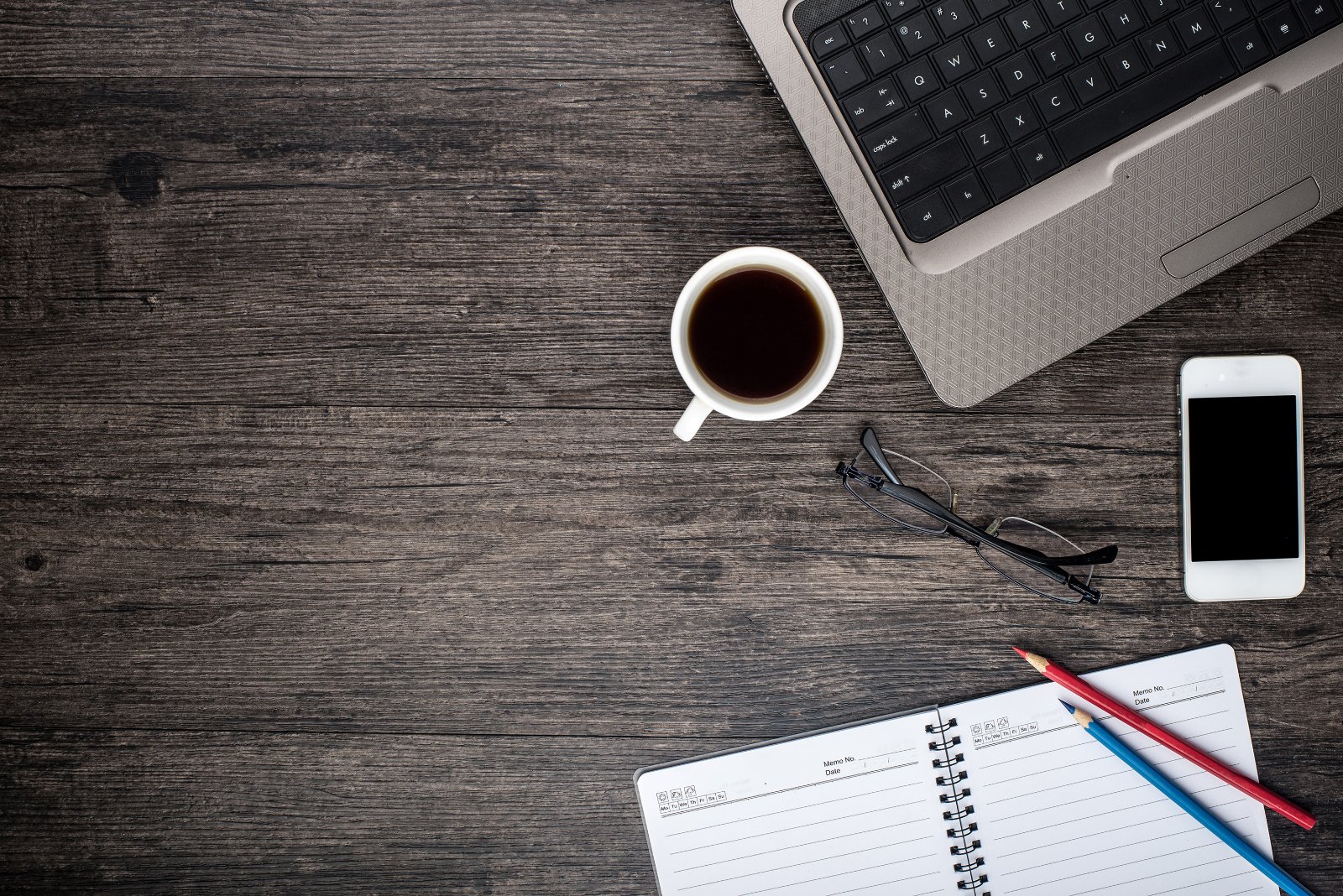 Scrivania in legno con computer portatile, tazza di caffe e blocco per appunti a righe